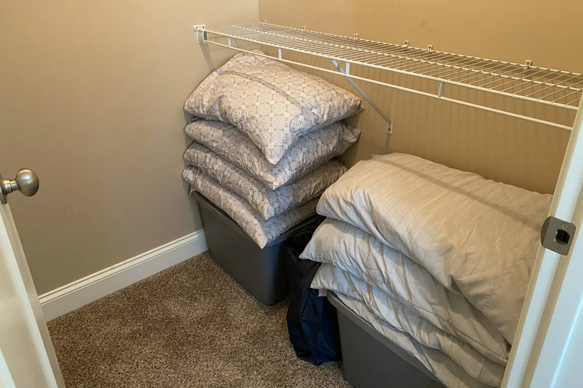 A neatly organized shelf stacked with pillows and storage bins, ready to provide guests with extra linens and bedding. The tidy arrangement suggests convenience and flexibility for group stays or changing guest needs.