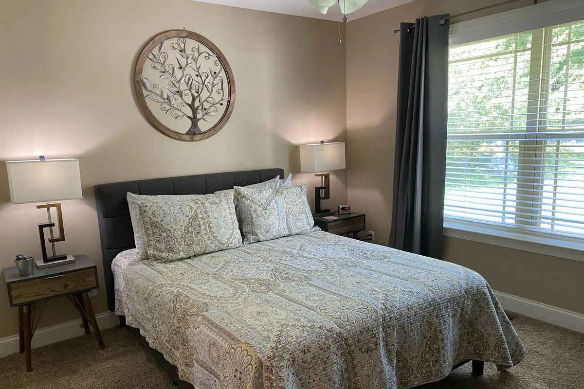 A tranquil bedroom scene highlighting a plush bed, stylish wall art, matching nightstands, and lamps. The overall setting radiates calm, inviting guests to relax, read, or enjoy a quiet cup of coffee in bed.
