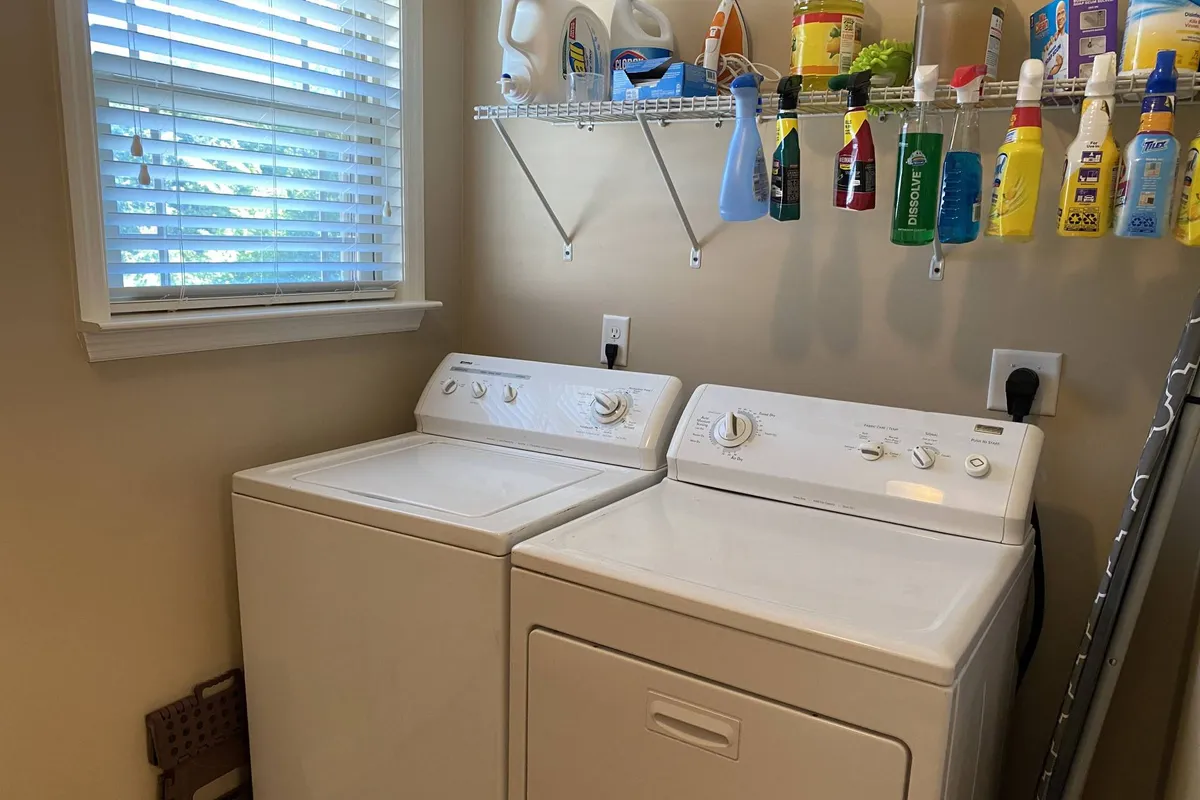 A practical laundry area is showcased here, with a washing machine and dryer, plus visible cleaning supplies. The scene highlights convenience and efficiency, suggesting the ease of maintaining fresh laundry during longer stays.