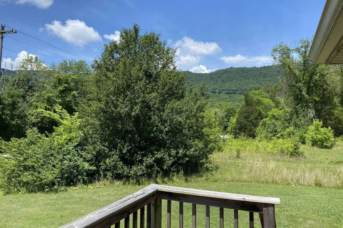 A peaceful outdoor view featuring lush greenery, distant mountains, and a clear blue sky, ideal for relaxing or setting out on nature walks.